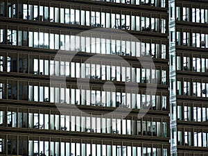 Windows of white lit offices in tall Office building viewed from outside