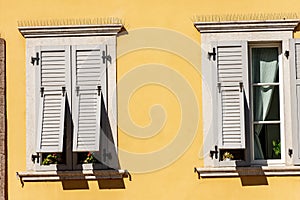 Windows with wooden grey shutters on orange wall - Trentino Italy