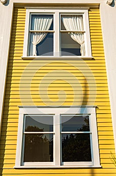 Windows. The Yellow wall with windows. Old looking yellow wall with white wooden windows with curtains