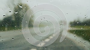 Windscreen wipers cleaning windshield glass on rainy day.