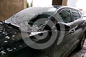 The windshield of the car is covered with light snow