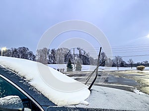 Windshield covered with snow and ice with the wiper blades raised to avoid freezing.