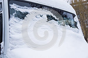 The windshield of the frozen minibus is covered with ice and snow on a winter day.