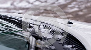 Windshield wiper blades with ice on blurred winter background