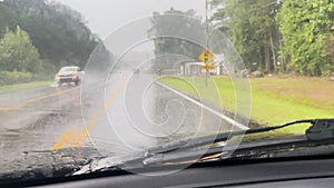 Windshield wipers wipe away heavy rain while car drives