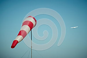 Windsock blown by the wind with airplane on a background