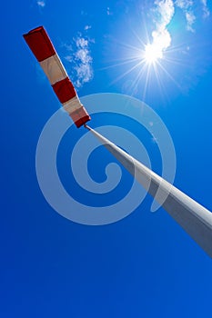 windsock in operation with strong blue sky background with sun