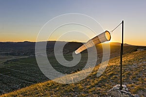 Windsock at sunset in mountains against sun