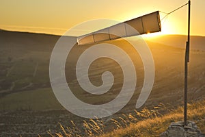 Windsock at sunset in mountains against sun