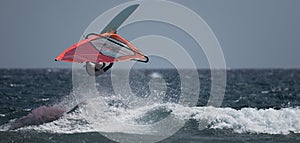 Windsurfer jumping over a big wave balancing