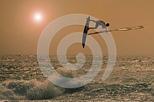 Windsurfer jumping in a sunset sky