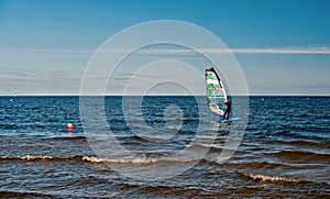 Windsurfer or man sportsman surfs and sails on board