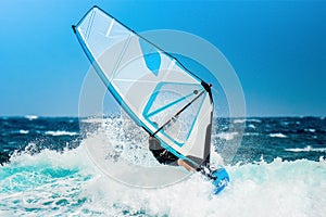 Windsurfer riding the waves with the white sail
