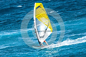 Windsurfer riding the waves with the yellow sail