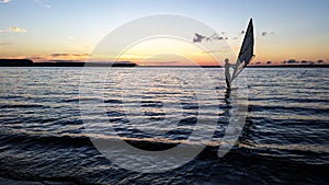 Windsurfer sailing in the lake at sunset.