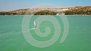 Windsurfer sails on ocean in coast direction