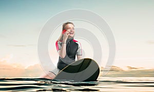 Windsurfer sitting on board and talks by phone