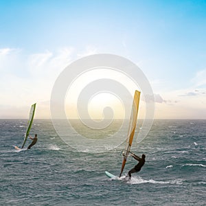 Windsurfer surfing the wind on emerald sea waves at the sunset