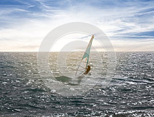 windsurfer surfing the wind on emerald sea waves at the sunset