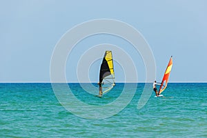 Windsurfing on the background of the sea landscape and clear sky.Two windsurfers men go in for sports, copy space