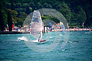 Windsurfing in front of the beach promenade in Torbole, Lake Garda, Italy