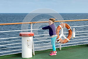 Windswept little girl hanging unto railing of ferry