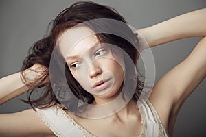 Windswept wonder. A beautiful young woman posing with hands in her hair.