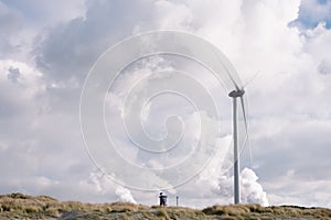 Windturbine with factories polluting against cloudy sky