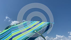 windy day at the beach with a striped cool color beach umbrella