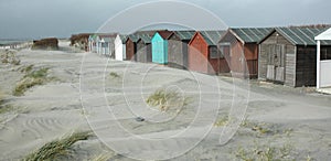 Windy day blowing sand on the beach with beach huts UK