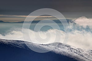 Windy snowfield above clouds and fog at dawn Slovak Carpathians