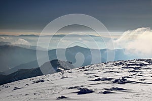 Větrné sněhové pole a mlhavé horské siluety ve Fatře na Slovensku
