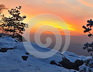 Windy winter morning view to East with orange sunrise. Daybreak in rocks