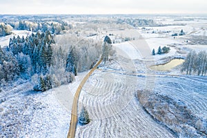 Windy winter road in snow covered forest, top down aerial view.