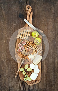 Wine appetizers set: cheese selection, honey, grapes, almonds, walnuts, bread sticks, figs on olive wood serving board
