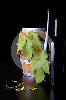 Wine, barrels and grape leaf, black background.