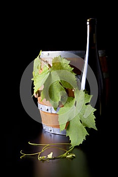 Wine, barrels and grape leaf, black background.