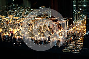 Wine and beer glasses on lit bar, lined up neatly