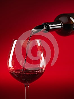 Wine being poured in glass red background photo