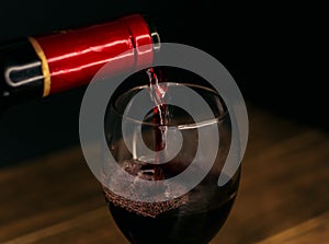 Wine bottle filling a glass on a black background