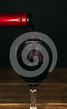 Wine bottle filling a glass on a black background
