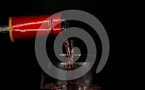 Wine bottle filling a glass on a black background. close-up