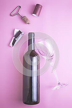 wine bottle glass glass stopper corkscrew chocolate and shrink cap on pink background