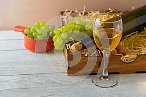 Wine bottle, glass, grapes in wooden box,