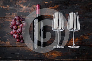 Wine Bottle and glass of Red wine with ripe grapes, on old dark  wooden table , top view flat lay