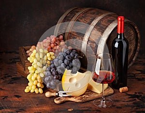 Wine bottle, grapes, cheese and glass of red wine