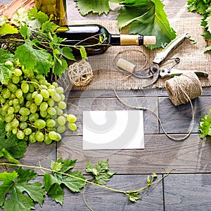 Wine bottle and grapes on wooden table. Top view with space for