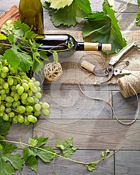 Wine bottle and grapes on wooden table. Top view with space for