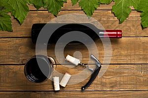 Wine bottle opener glass stoppers and vine leaves on wooden background. Top view with copy space