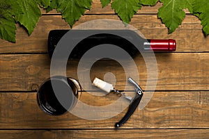 Wine bottle opener glass stoppers and vine leaves on wooden background. Top view with copy space